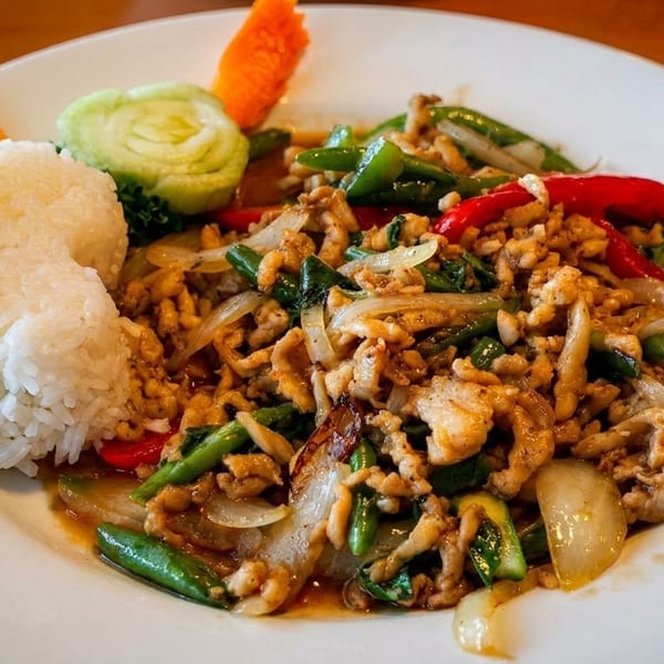 A white plate with a serving of stir-fried chicken, green beans, onions, and red peppers, alongside white rice.