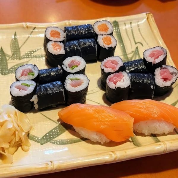 A platter of various sushi rolls and salmon nigiri, with wasabi and pickled ginger.